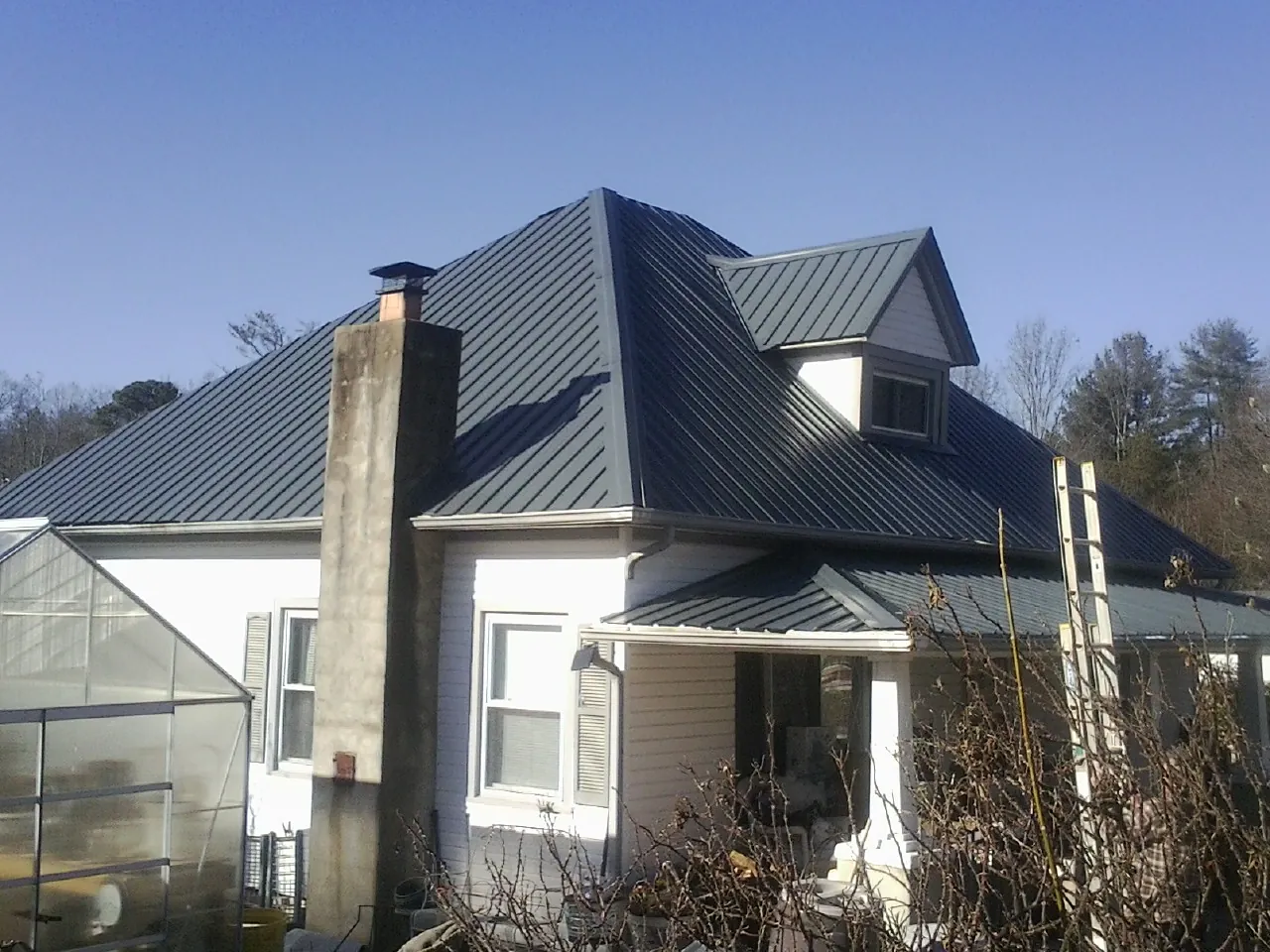 Dark blue standing seam metal roof on a white farmhouse with dormer — Slate & Tile Roof Repair by Roofing Brothers in Rathdrum