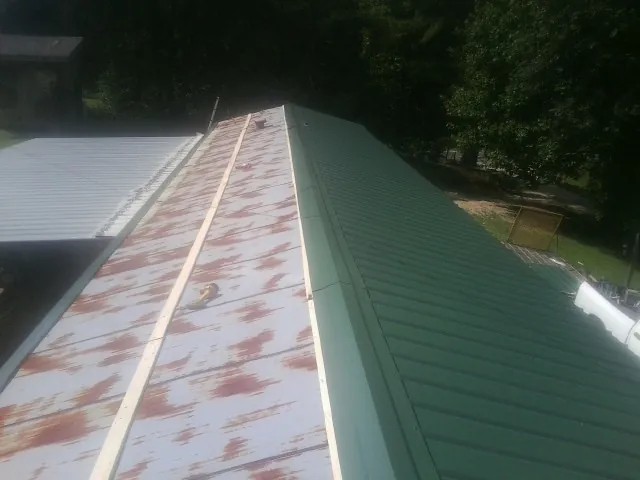 Old rusted panels beside newly installed green metal roofing — Wind Damage Roof Repair by Roofing Brothers in Rathdrum