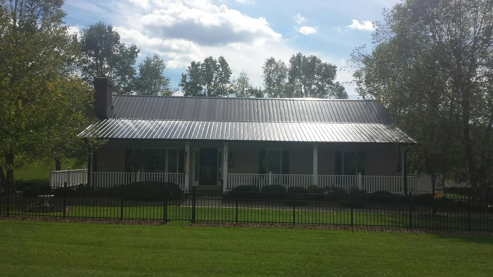 Gray metal roof on a brick ranch with a full width front porch — Gutter Guard Installation work by our crew in Rathdrum