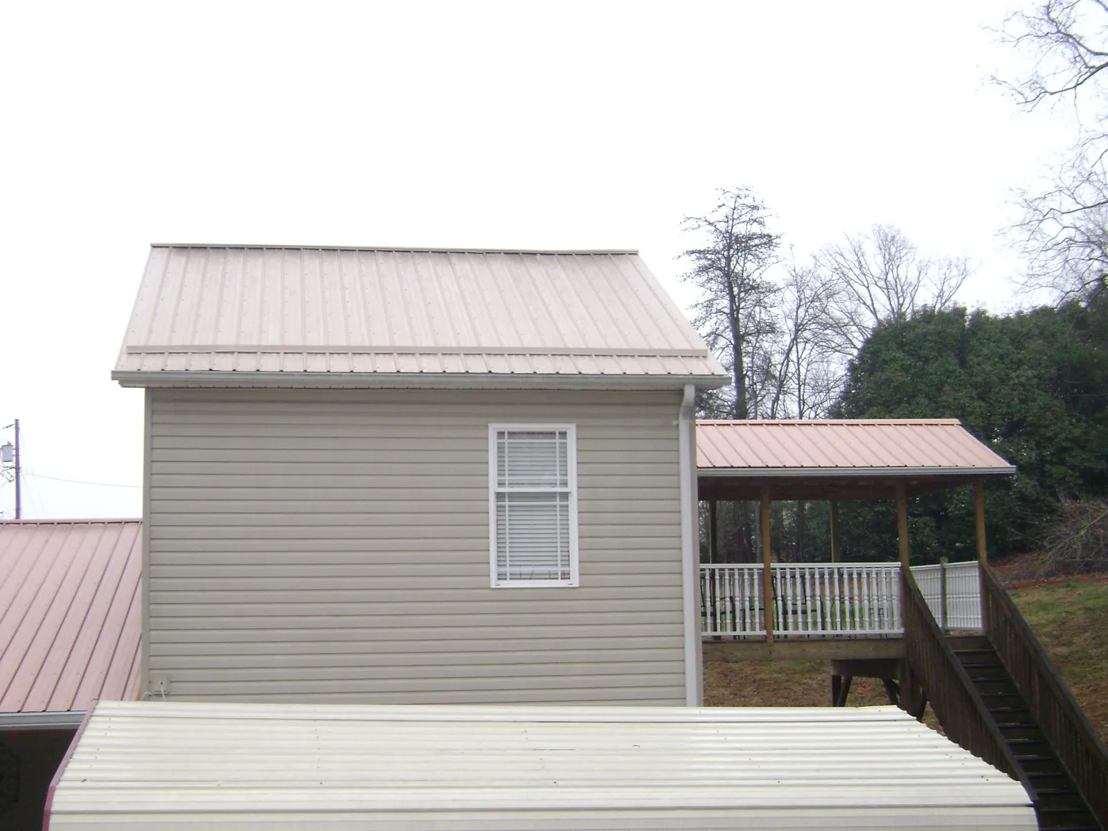 Tan metal roofs on a two story addition and attached porch, from a Roof Replacement job in Rathdrum