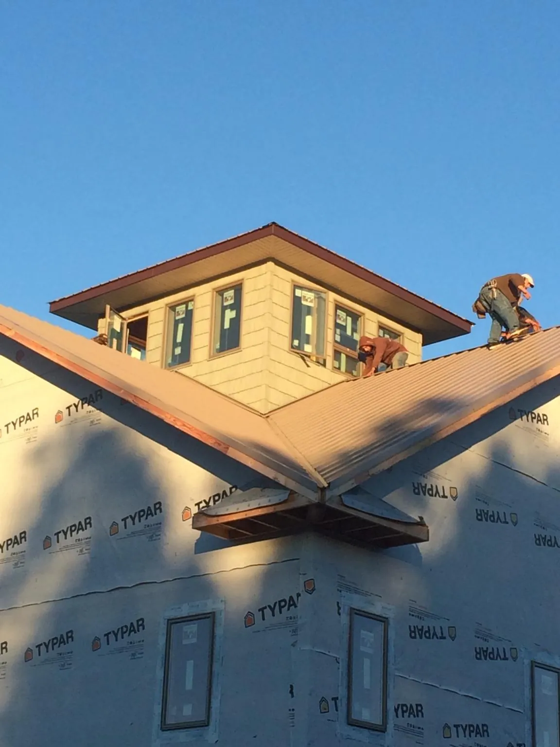 Roofers working around a rooftop cupola on a new metal roof at sunset — Roof Waterproofing in Rathdrum by Roofing Brothers